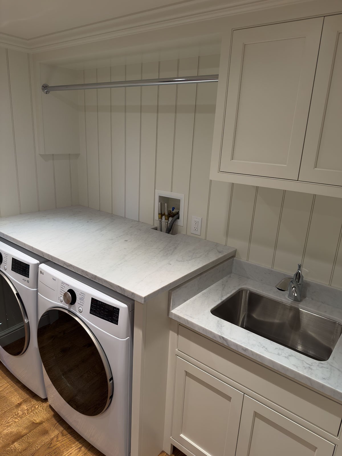 White Carrara marble countertop in laundry room with undermount sink and white cabinets, Weston Massachusetts