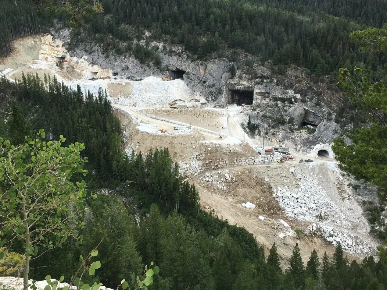 Colorado marble quarry at 9,300 feet in the Rocky Mountains showing mine entrances, marble blocks, and equipment surrounded by evergreen forest - source of Calacatta Lincoln marble used in the Lincoln Memorial