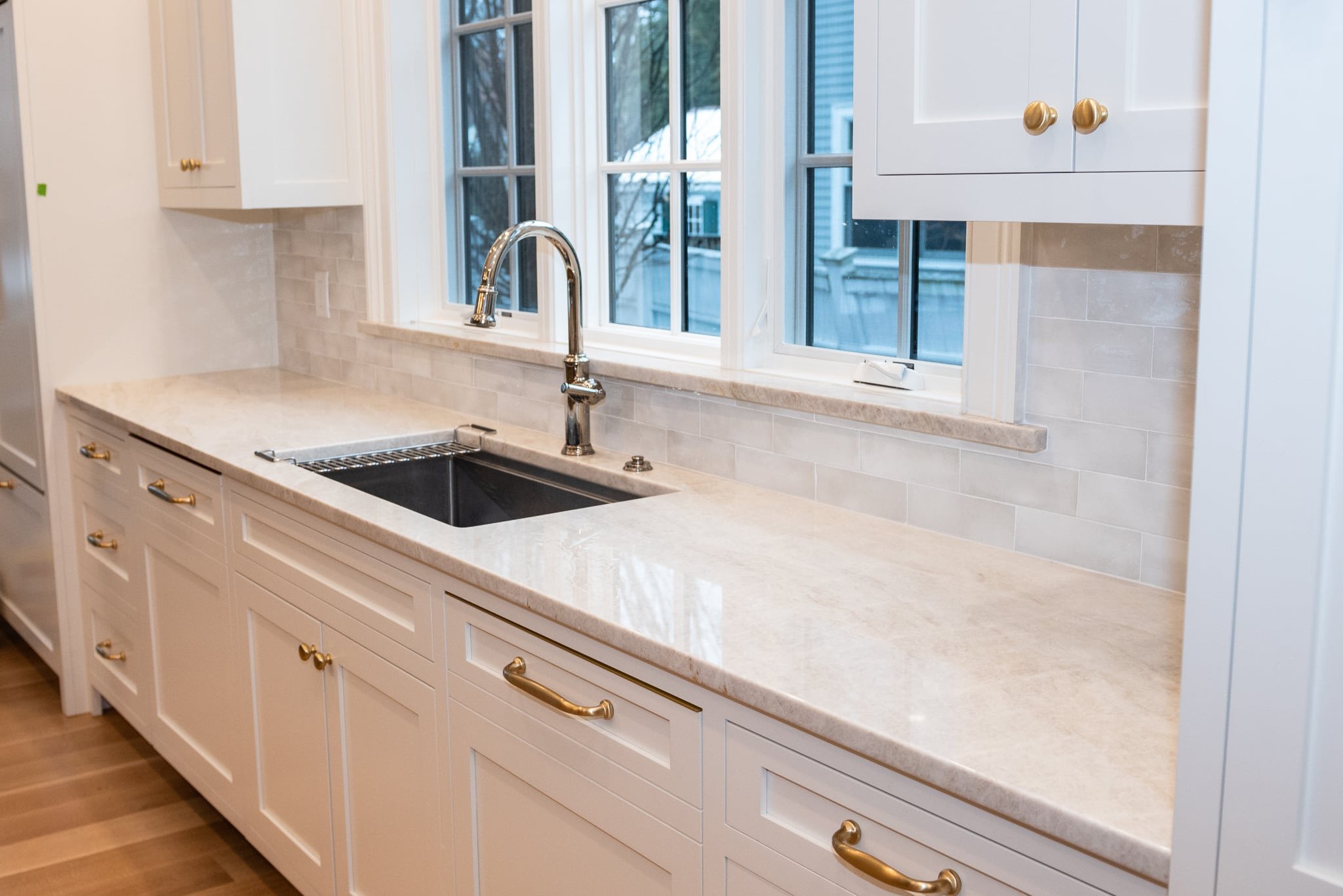Polished Taj Mahal quartzite pantry countertop featuring an undermount sink, chrome faucet, and gold hardware in a Needham home.