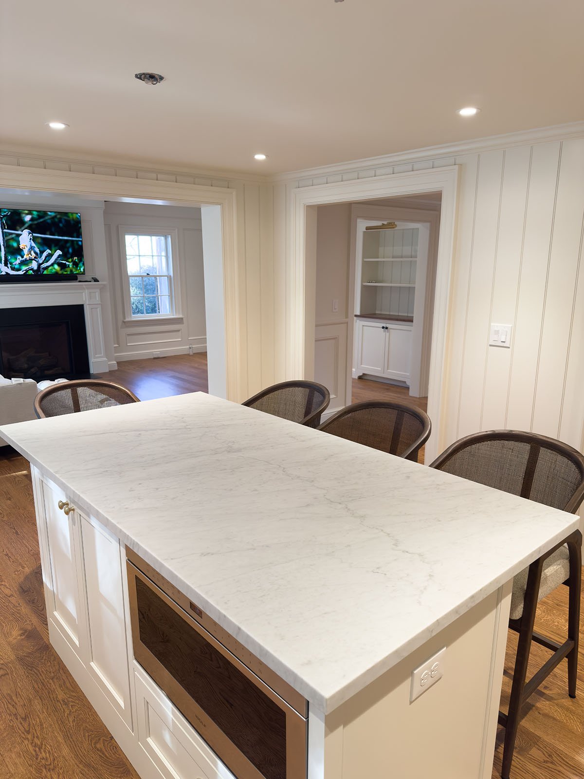 White Carrara marble kitchen island with mitered edge and seating, open concept living space, Weston Massachusetts