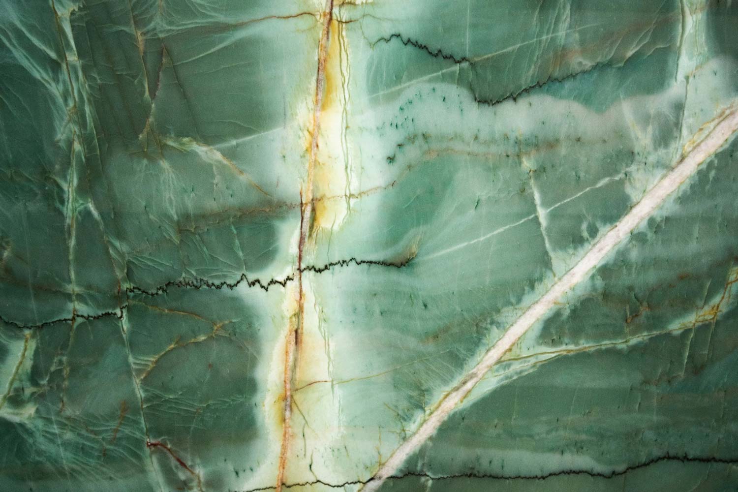 Da Vinci quartzite countertops with deep green hues, gold accents, and bold veining, perfect for kitchen countertops by Granite Guy Inc.