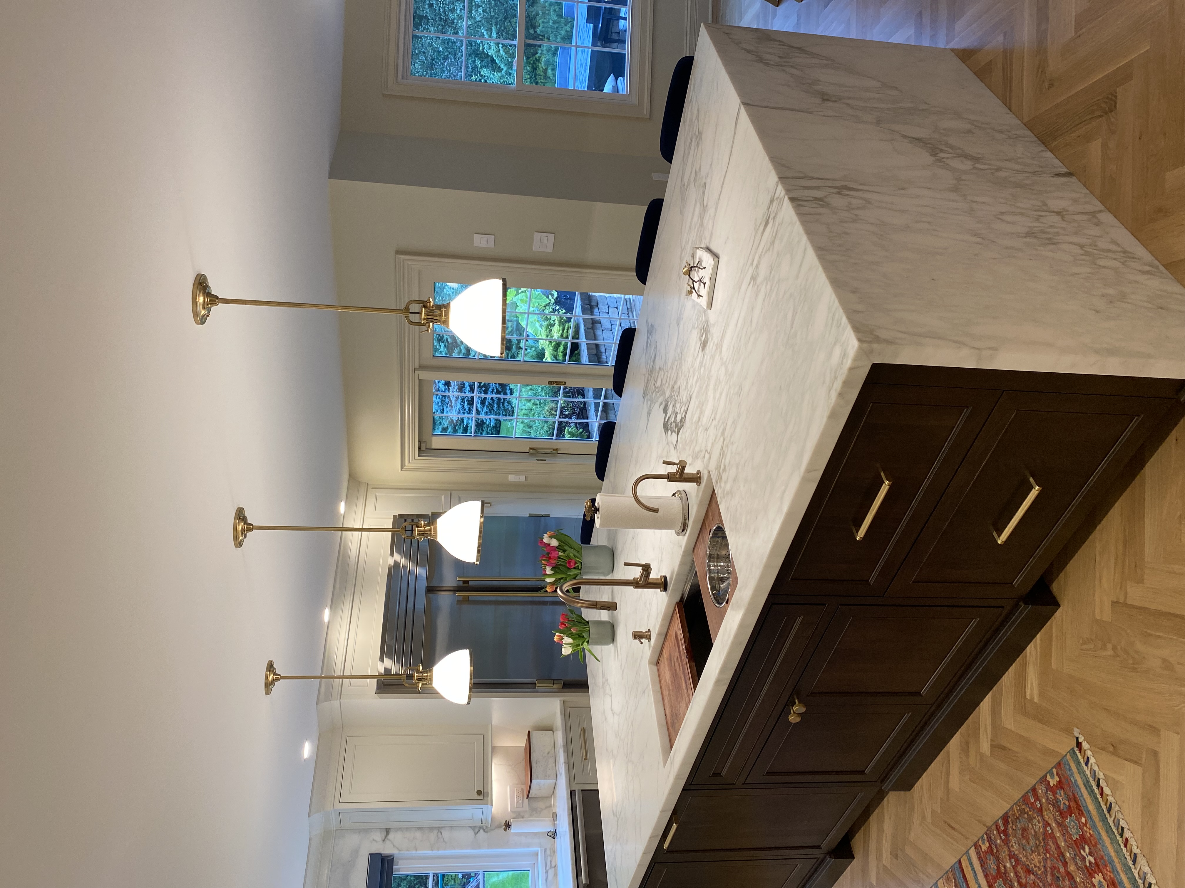 Calacatta marble waterfall kitchen island with dark wood cabinetry and brass fixtures. Kitchen countertops by Granite Guy Inc.