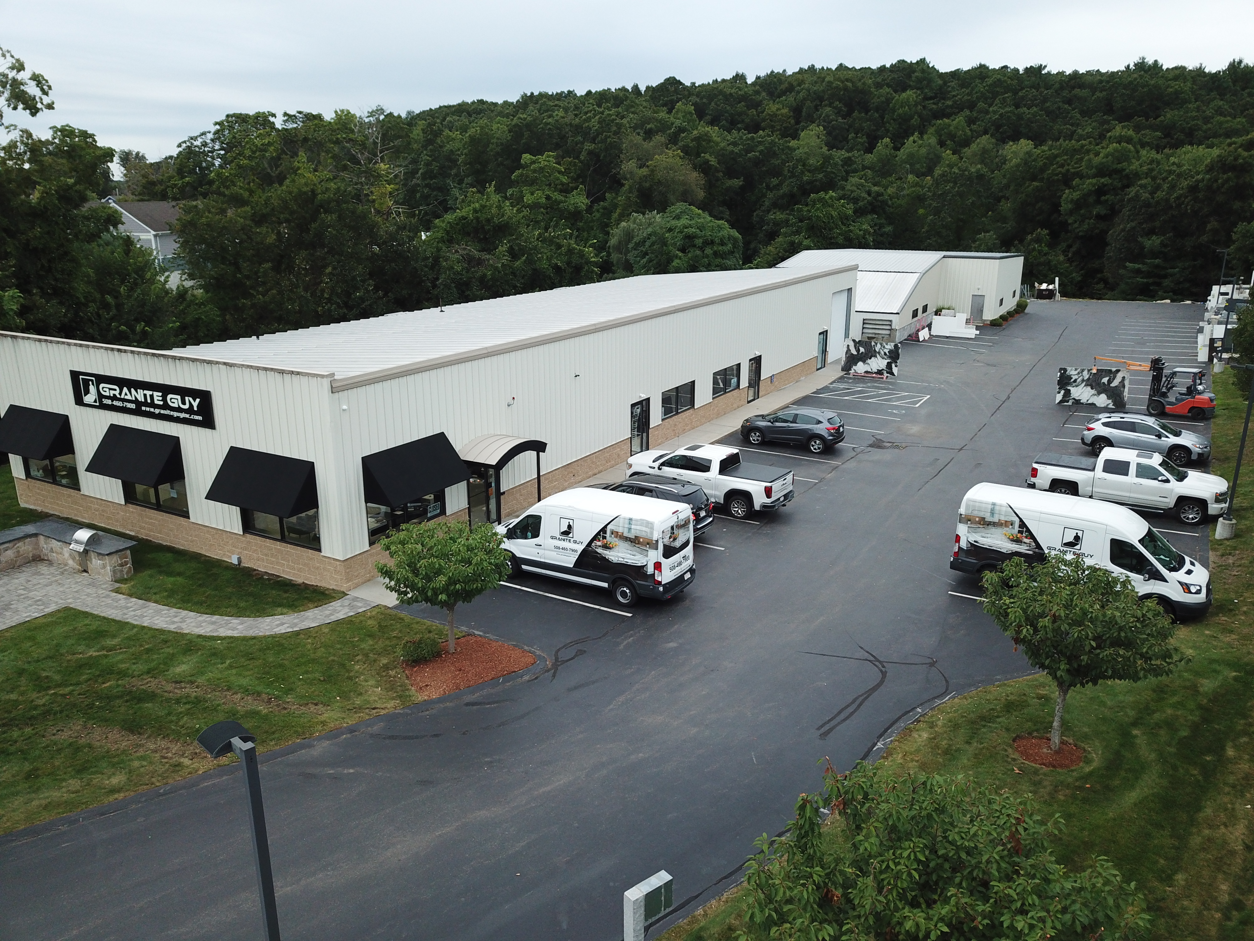 Granite Guy Inc. showroom and stone fabrication facility in Southborough, MA, featuring branded vans and modern warehouse.