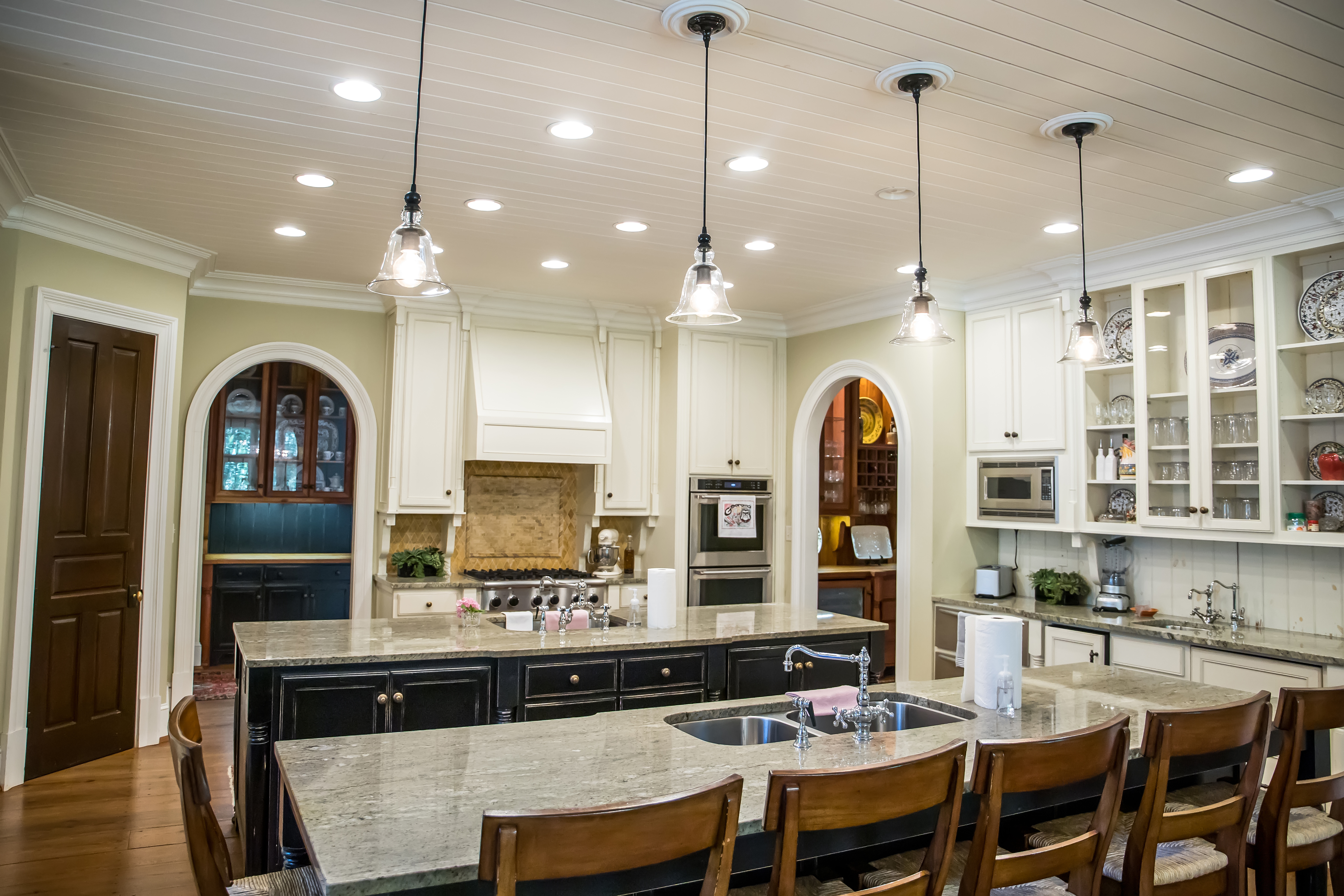Traditional kitchen with granite countertops, white cabinetry, double islands, and pendant lighting. Granite countertops by Granite Guy Inc.